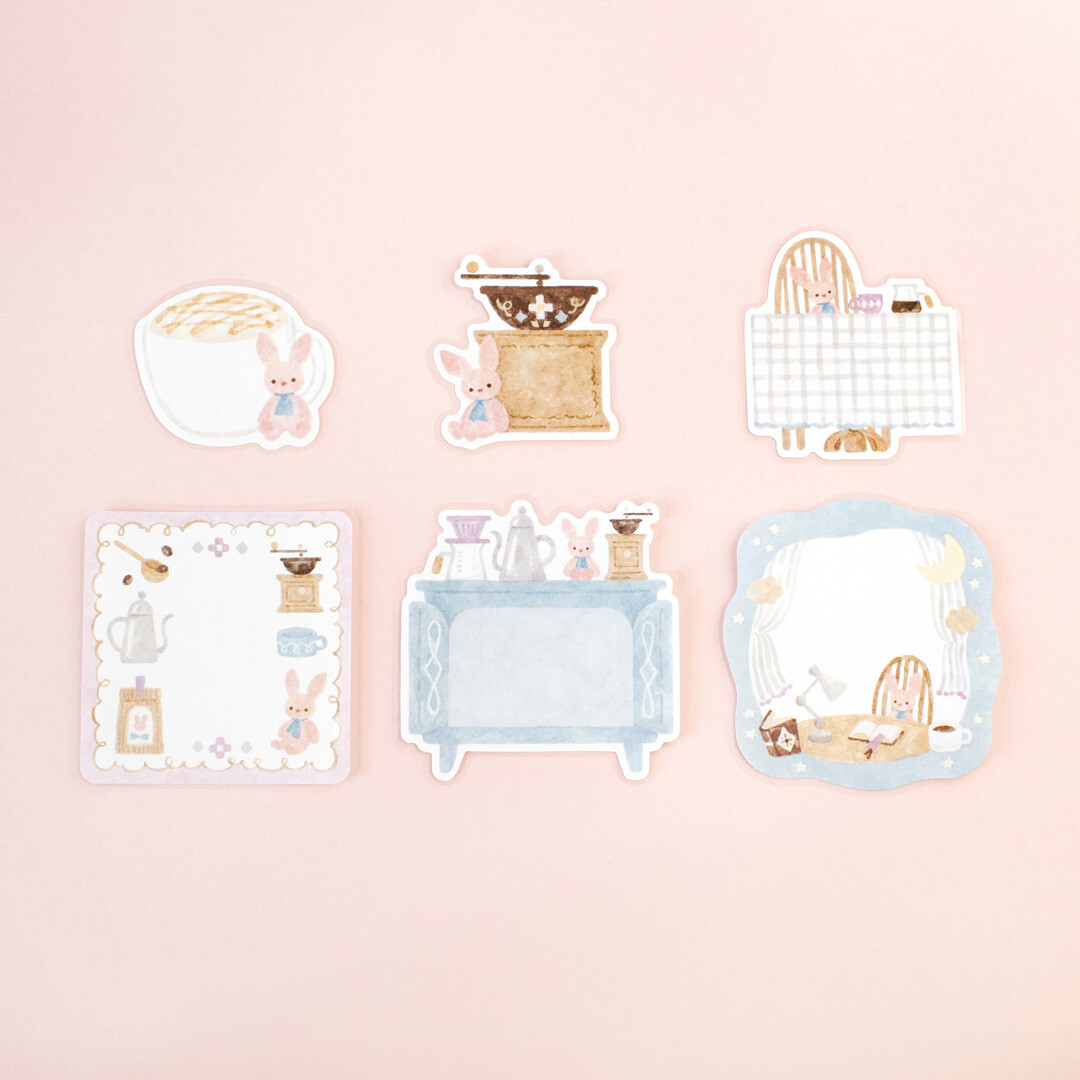Individual Papier Platz Rabbit’s Café stickers laid out on a pink background, showing rabbits enjoying café scenes with coffee grinders, tables, notebooks, kitchen counters, and cosy interior details.