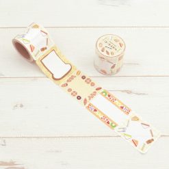 Papier Platz PuPuPu sticky roll labels with sandwich and pastry illustrations, roll partially unwrapped on wooden background.
