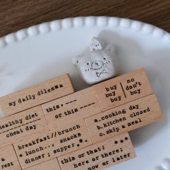 Close-up flat lay of Eileen Tai My Daily Dilemma rubber stamps arranged on a ceramic plate.